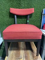 Front view of the overstuffed red fabric chair showing cushioned seat and backrest with wooden legs and frame.