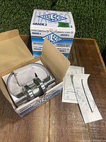 Boxed set of Halsco Grade 2 passageway door handles on table with green grass background.