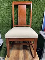 Full view of the wooden dining chair showing the backrest design and wooden legs, with some scuffs on lower edges.
