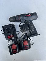 Ryobi cordless drill with two 9.6V batteries and charger on white background