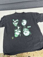 Photo of black Kiss band t-shirt with graphic print of four band members' faces in makeup.