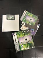 Men In Black The Series Game Boy Advance game cartridge, original case, and manuals displayed on black surface.