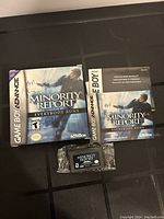 Game Boy Advance Minority Report game cartridge, original box, and instruction booklet laid out on a dark surface.