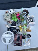 Full overview of all toy items on a table showing various action figures, plush toys, gaming controllers, and collectible figures.