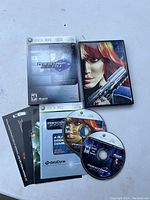 Xbox 360 Perfect Dark game case, two game discs, and user manual laid out on a flat surface.