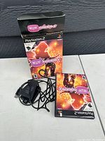 Packaged PlayStation 2 Dance Dance Revolution game with case, box, and power adapter cable visible