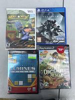 Photo of four sealed video game cases arranged on a flat surface including Wii, PS4, and PS2 titles.