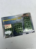 Photo of Alaca brand sports pedal pad set in original packaging with three metal pedal pads in green metallic color with black rubber dots