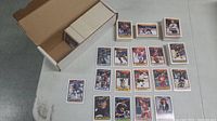 Overview photo showing several hockey cards laid out on table with box of cards visible, showing card style and design with player images and names.