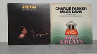 Photo showing both vinyl LP album covers together. Left is Aretha Franklin's 'Live at Fillmore West' with image of Aretha singing. Right is Jazz Greats album featuring Charlie Parker and Miles Davis with pastel wave design and 'Hall of Fame' emblem.