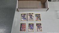 Box with large stack of hockey cards, and six individual cards, including players in NHL team uniforms