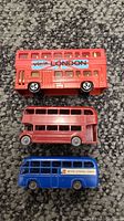 Three vintage toy buses lying on the floor carpet, showing top, middle, and bottom views.