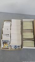 Box of stacked football cards including rookie cards at front, showing quantity and general condition