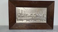 Frontal view of raised metal artwork depicting The Last Supper in a wooden frame.