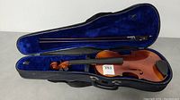 Violin and bow inside blue-lined hard case, showing overall fit and completeness.