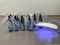 Front view of multiple sealed resin bottles and LED UV lamp turned on emitting blue light on table.