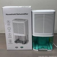 Full front view of dehumidifier alongside its box showing product features and design.