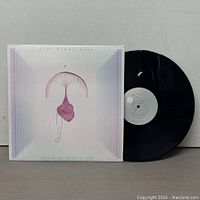 Vinyl record disc partially out of the sleeve showing the black vinyl and label.