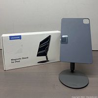 Showing the Lululook Magnetic Stand holding a tablet upright next to the product box.