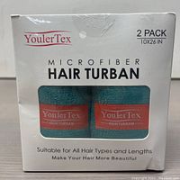 Front view of the box showing two turquoise microfiber hair turbans side by side with YoulerTex branding visible through window.