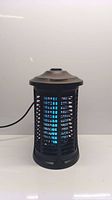 Front view of the black mosquito killer bug zapper with blue UV light turned on