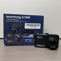 Ssontong A16W dash cam alongside its original box showing front and partial side views of the camera and printed packaging details.