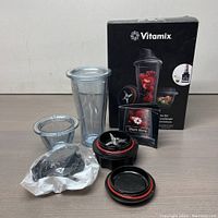 Full kit arranged with box, including cups, lids, blade assembly, and manual