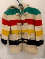 Full view of the child's wool coat with distinctive colored stripes and toggle closures, showing overall design and condition.