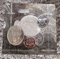 Front view showing six Canadian coins from 1962 embedded in clear Lucite block with visible coin faces, including penny and nickel.