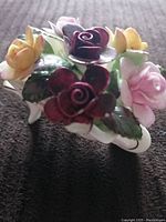 Top view of the Royal Albert porcelain wheelbarrow showing detailed colorful flowers in pink, yellow, and dark red with green leaves.