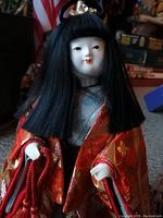 Front view of vintage Japanese Warabe doll, showing detailed face, black hair, and red and gold silk kimono.