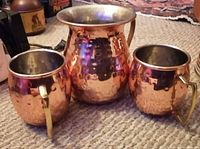 Photo showing the copper jug with two matching mugs arranged on carpeted floor.