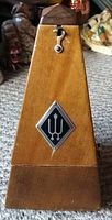 Front view of vintage Wittner wooden metronome with logo and winding key.