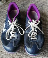 Pair of navy blue Nike women's shoes viewed from the front-top showing white laces and purple interior lining.