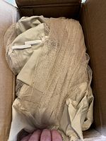 Mosquito net fabric and pieces inside a cardboard box showing the folded beige mesh netting.