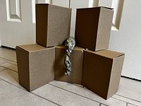 Five cardboard boxes with one decorative elephant piece draped over the middle box showing the length and size