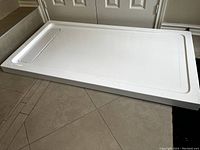White rectangular 32x60 inch shower pan base photographed from an angle showing depth and flat surface.
