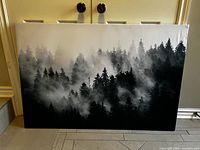 Larger canvas print depicting a black and white foggy forest landscape with dense conifer trees in mist.