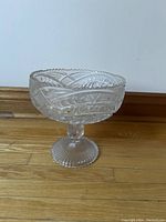 Front angle view of the vintage crystal glass pedestal fruit bowl showing detailed cut glass patterns and scalloped rim.