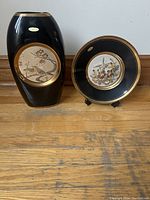 Vase and plate side by side showing overall design and color scheme of black with gold accents