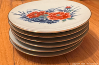Stack of six plates highlighting floral design and gold trim