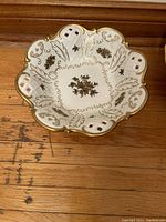 Top view of the porcelain bowl showing scalloped edge, lattice cut-outs, and gold ornate pattern.