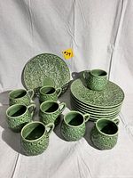 Overview of set showing stacked plates and arranged mugs on white background
