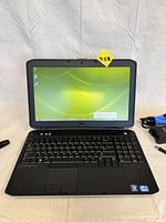 Photo of Dell Latitude E5530 laptop powered on showing Windows desktop screen and keyboard with numeric keypad, showing screen and laptop condition.