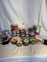 Overview of large lot of assorted ribbon spools showing colors, patterns, and textures including velvet, mesh, satin, and printed ribbons.