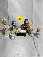 Full set of seven vintage Hummel Christmas figurines including nativity scene and angels, displayed on neutral backdrop.