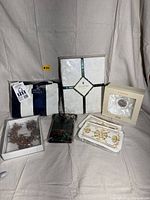 Shows all the items in the lot: bedding, napkins, jewelry sets, boxed candle, wallet on a light cloth background