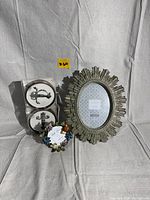 Lot items shown together: ornate oval Bella Lux picture frame, Met Museum of Modern Art coasters, decorative coaster with fruit design.