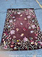 Full view of the brown floral and butterfly patterned rug.