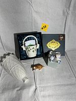 Four porcelain items shown: tall white vase, shamrock basket in box, brown dog figurine, Lladro box with figurine